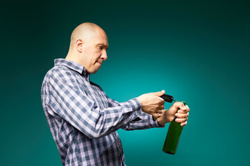 a man tries to open a beer bottle with a car key isolated on green background in studio .