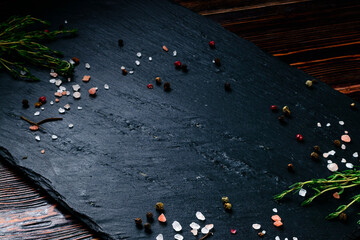 empty black slate with pepper, salt and rosemary. Herbs and spices for cooking. Cooking concept template
