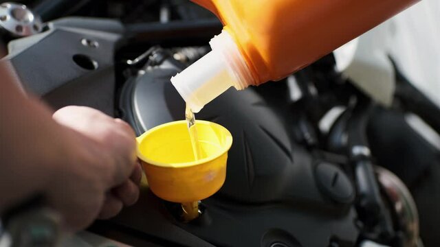 Biker change engine oil on motorcycle. Pouring oil to motorcycle engine.