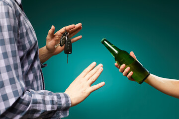 Man refusing alcohol beer showing car key as gesture of don't drink and drive isolated over green...