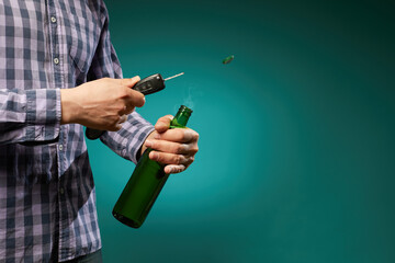 a man tries to open a beer bottle with a car key isolated on green background in studio .