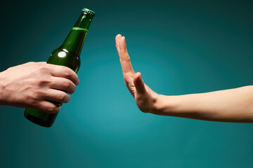 Female rejecting bottle beer showing stop gesture isolated over green background with copy...