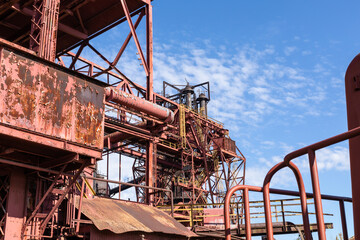 Fototapeta na wymiar Expansive industrial steel manufacturing facility, rusted beams and girders, vivid blue sky, horizontal aspect