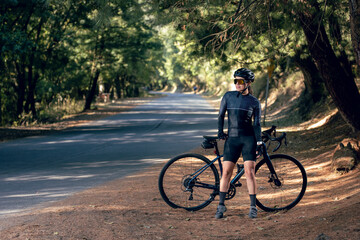 chica posando con bicicleta al lado de la carretera en medio del bosque, usando casco y lentes de sol