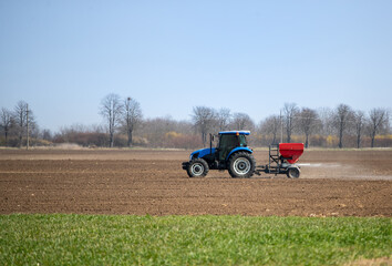 Tractor spreading artificial fertilizer in field