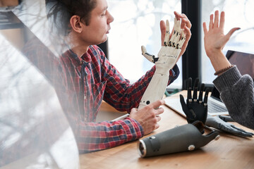 Engineer looking at the prosthesis hand and comparing it with real hand