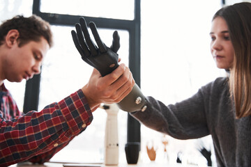 Male engineer putting a prosthesis on a woman's hand