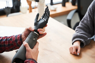 Male engineer holding a prosthesis of a hand while testing it