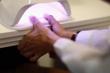 Fototapeta premium Close-up of manicurist covering nails of client with nail polish