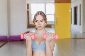 Fototapeta na wymiar Girl doing exercise with dumbbells in the gym. Sport, healthy lifestyle concept