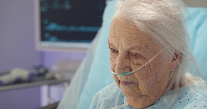 Close up portrait of sad and depressed sick aged woman lying in hospital bed