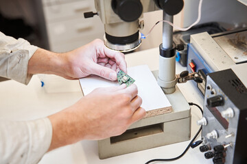 Engineer wearing white robe looking at the microscope at the schema