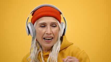 Smiling woman listening music in headphones indoors. Joyful lady dancing inside.