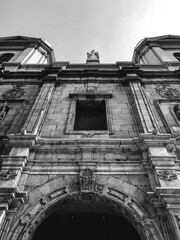 Details in the front entrance of the old Santo Domingo Church in Santiago downtown with two women walking, Chile (in black and white)