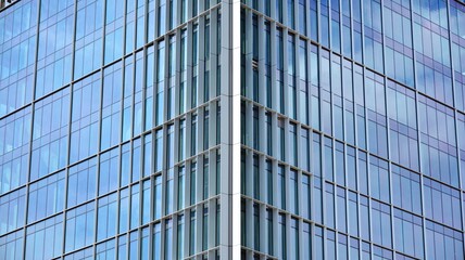 Glass clad facade of a modern building covered in reflective plate glass.