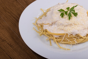 Pasta with bechamel sauce with grated cheese and parsley leaves. Close-up photo with food on the right. Popular food.