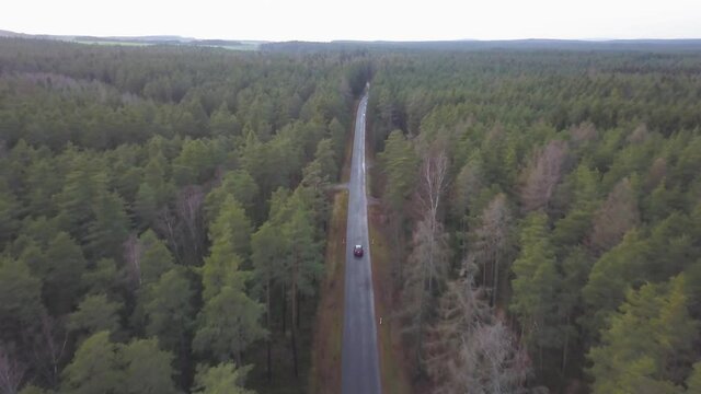 Car driving through a forest street in bavaria, topdown follower drone