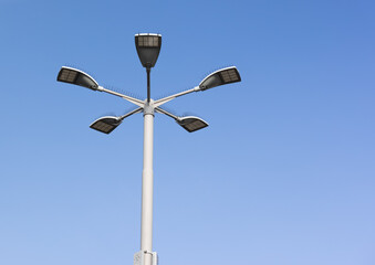 big round star shaped light pole with 5 led lamps in front of blue sky during the day, the lamps are switched off
