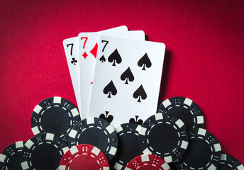 Obraz premium The winning poker combination is three kind or set. Chips and cards on red table in poker club