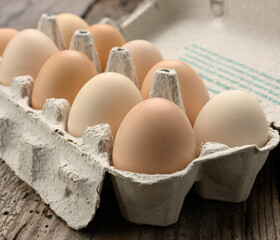 fresh whole brown eggs in paper packaging on a gray wooden background
