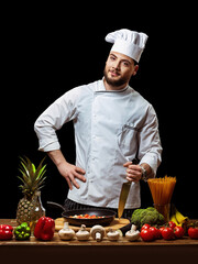 A chef in a white uniform prepares vegetables. Isolate on black background 