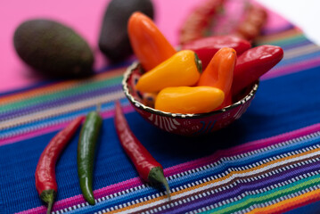 presentation of multicolored peppers, avocado guacamole on pink and backgrounds