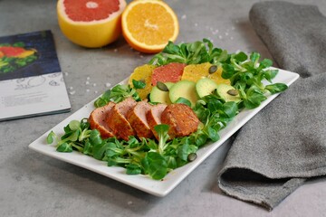 Fresh salad with lettuce, orange, grapefruit, avocado a port fillet on white plate