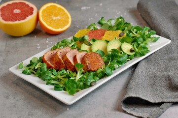 Fresh salad with lettuce, orange, grapefruit, avocado a port fillet on white plate