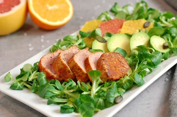 Fresh salad with lettuce, orange, grapefruit, avocado a port fillet on white plate