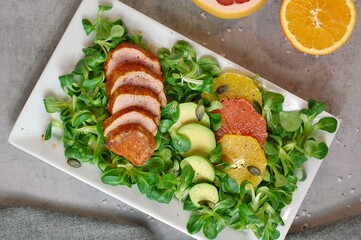 Fresh salad with lettuce, orange, grapefruit, avocado a port fillet on white plate