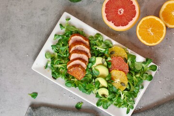 Fresh salad with lettuce, orange, grapefruit, avocado a port fillet on white plate