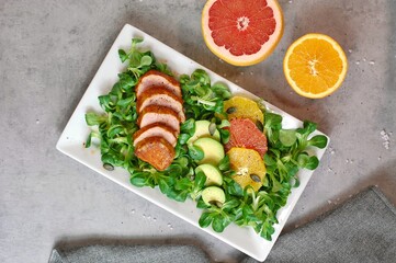 Fresh salad with lettuce, orange, grapefruit, avocado a port fillet on white plate