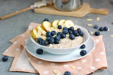 Creamy buckwheat porridge with pear, blueberry and almond in white bowl