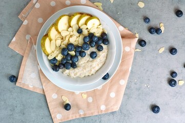 Creamy buckwheat porridge with pear, blueberry and almond in white bowl