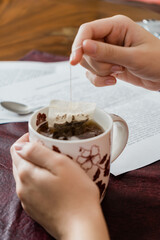 Young woman having tea with cookies while working with her contract