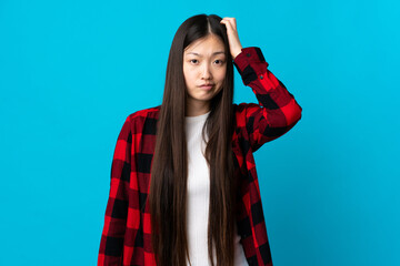 Young Chinese girl over isolated blue background with an expression of frustration and not understanding