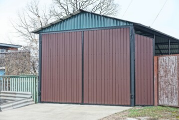 facade of a private garage with closed brown metal gates on the street