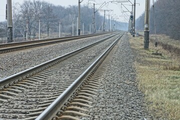Fototapeta premium Railway track with rails and sleepers, covered with gray stones and brown grass