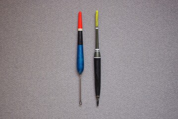 two long colored plastic fishing floats lie on a gray table