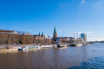 View from footbridge to river weser with some boats in the sunlight in bremen in winter - obrazy, fototapety, plakaty