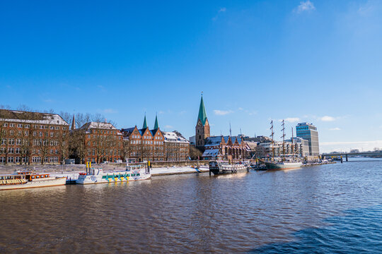 View from footbridge to river weser with some boats in the sunlight in bremen in winter