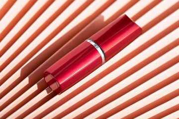 Red lipstick tube mockup on chinese paper fan texture background with shadow, luxury cosmetic...