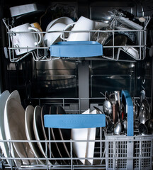 Dirty dishes, plates and cups in dishwasher. Housekeeping and Modern Domestic Kitchen Appliance concept. 