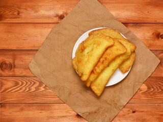 freshly baked pasties on a white plate against the background of kraft paper and a wooden table. rustic style.