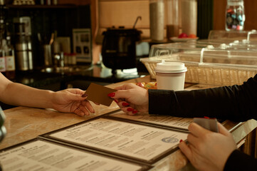 Close-up of a female customer presenting a credit card in a cafe