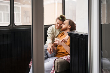 Woman sitting at the armchair at the balcony with her husband and bonding to him