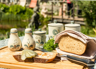 Fat cuts of lard bread on a wooden board decorated with bread, cucumber, salt and pepper and other spices