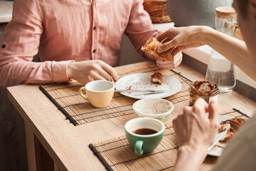 Fototapeta na wymiar Gay couple enjoying breakfast together while drinking coffee and eating croissants