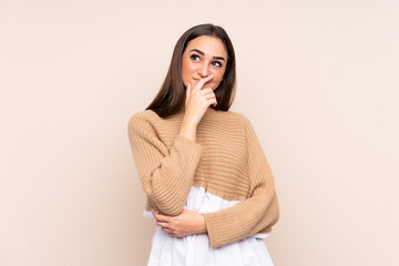 Young caucasian woman isolated on beige background having doubts and with confuse face expression