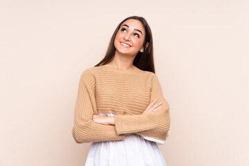 Obraz premium Young caucasian woman isolated on beige background looking up while smiling